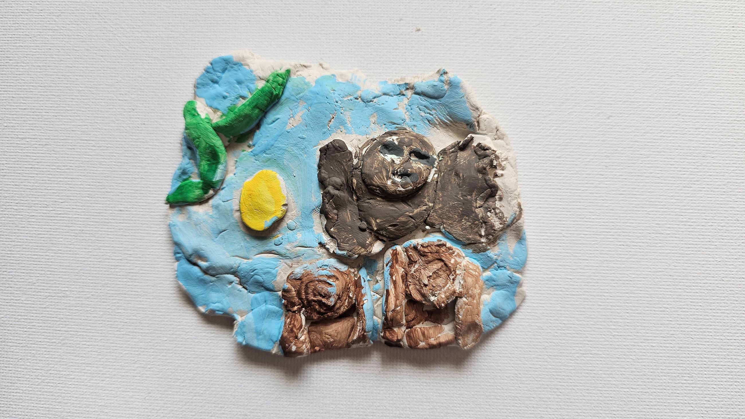 Colorful clay artwork with bird-like figure, plants, and tree stumps