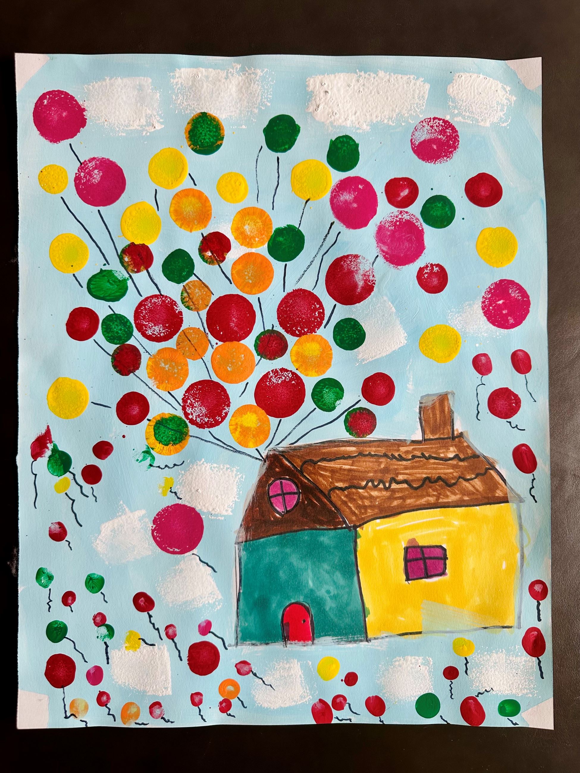 Colorful house with balloons floating against a blue sky with clouds